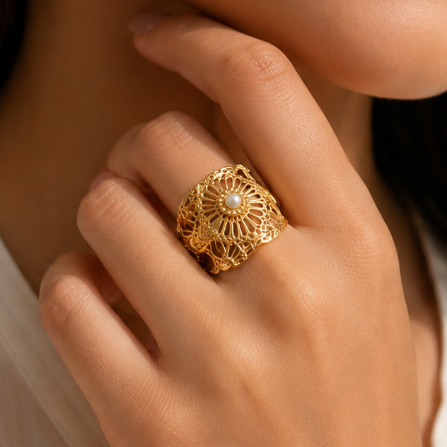A close-up lifestyle shot of a woman wearing a large, ornate gold ring with a sunburst filigree design on her finger.