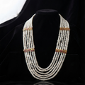 A multi-strand pearl necklace with gold-toned accents displayed on a black velvet jewelry bust.